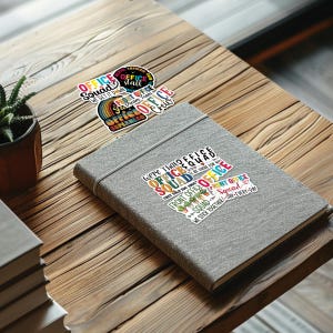 May include: A set of four colorful stickers with text that reads "Office Squad" and "We Get It Down" and "Front Office Dream Team" and "Office Superhero Crew". The stickers are on a gray notebook with a sticker that reads "We're That Office Squad They Told You About You'll Be There For Us Front Office Squad We Stick Together - Day - Every - Day".