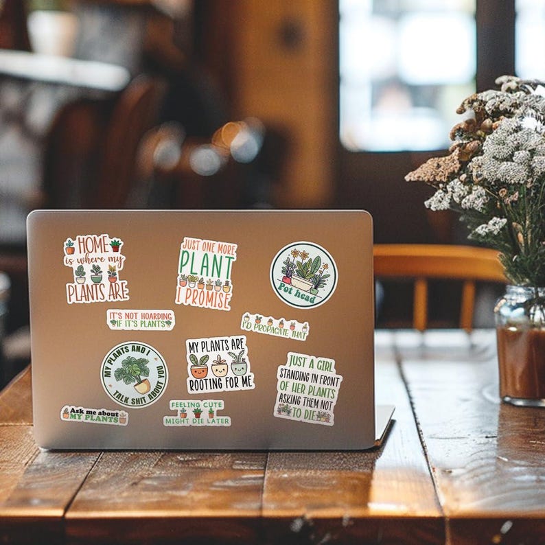 May include: A laptop computer with several stickers on it. The stickers feature illustrations of plants and text about plants. The text on the stickers includes: "Home is where my plants are", "Just one more plant I promise", "My plants are rooting for me", "Just a girl standing in front of her plants asking them not to die", "Pot head", "My plants and I talk shit about you", "Ask me about my plants".