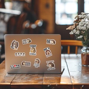 May include: A silver laptop computer with multiple hedgehog-themed stickers. The stickers feature various hedgehog illustrations and text such as "I love hedgehog", "Hedgehugs", "Living on the hedge", "Sorry, my hedgehogs are my homework", "I'm with the hedgehog", "Not a hugger", "Hedgehogs are my favorite animal", "I'm feeling a bit prickly today", and "Who wants to share the hedge?"