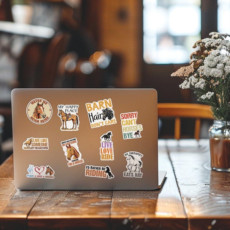 K&ouml;nnte beinhalten: Ein Laptop-Computer mit einer Vielzahl von Pferdemotiven-Aufklebern. Die Aufkleber zeigen S&auml;tze wie "Watch Me Neigh Neigh", "My Happy Place", "Barn Hair Don't Care", "Sorry Can't Horses Bye", "Live Like Someone Left The Gate Open", "Horses Are Awesome I'm A Horse", "Live Love Ride", "I'd Rather Be Riding", und "My Therapist Eats Hay".