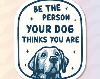 May include: A sticker with a white background and a blue border. The text reads "BE THE PERSON YOUR DOG THINKS YOU ARE" above a blue and white illustration of a dog's face.