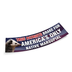 Op de afbeelding: Een gebogen sticker met een rood, wit en blauw Amerikaans vlagontwerp. De sticker toont een opossum met de tekst "TRUE PATRIOTS BRAKE FOR AMERICA'S ONLY NATIVE MARSUPIAL" in rood en wit.