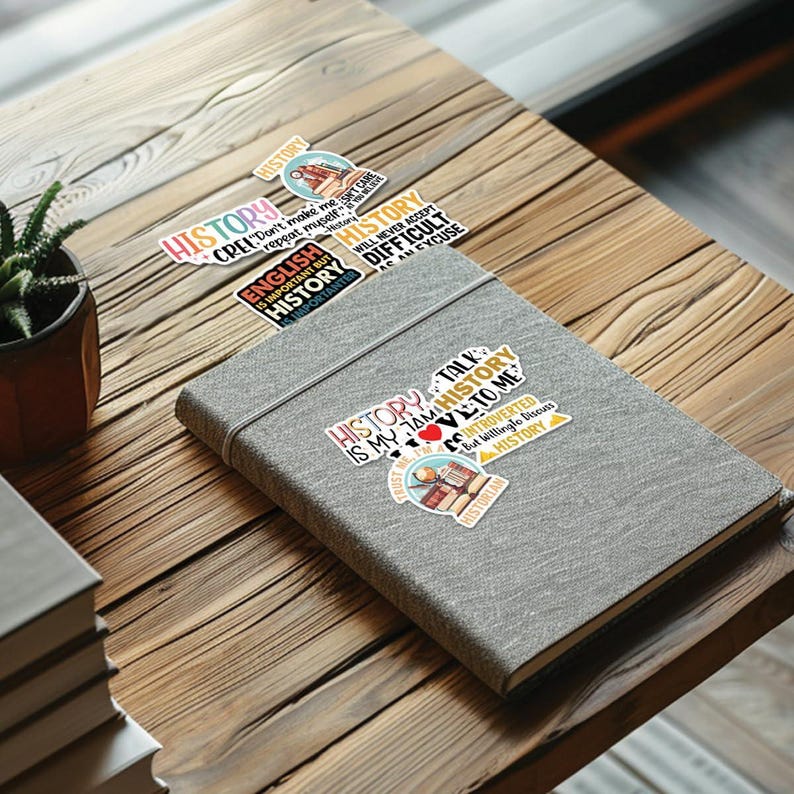 May include: A collection of colorful stickers with text about history. The stickers are on a gray notebook. The text on the stickers includes "History is my jam", "History talk to me", "Introverted but willing to discuss history", "English is important but history is more important", "Don't make me repeat myself", "History will never accept difficult as an excuse".