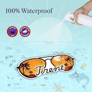 May include: A personalized sunglasses sticker with the name "Trent" in white script. The lenses feature a sunset scene with palm trees. The sticker is labeled "100% Waterproof" and "Car Wash Safe."