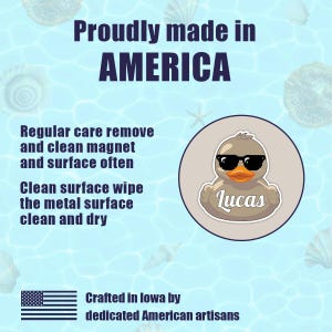 Puede incluir: Un fondo azul claro con conchas marinas y texto que dice "Proudly made in AMERICA". Un pato de dibujos animados con gafas de sol est&aacute; en un c&iacute;rculo con el nombre "Lucas". El texto tambi&eacute;n dice "Crafted in Iowa by dedicated American artisans".