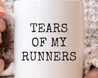May include: White ceramic mug with black text that reads "Tears of my runners".