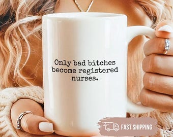May include: White ceramic mug with the text "Only bad bitches become registered nurses." The mug has a large handle and is held by a person. The mug is a standard size for coffee or tea.