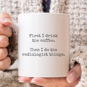 May include: White ceramic coffee mug with black text that reads "First I drink the coffee. Then I do the radiologist things."