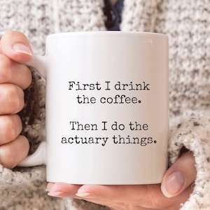May include: White coffee mug with black text that reads "First I drink the coffee. Then I do the actuary things."