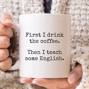 Könnte beinhalten: Eine weiße Kaffeetasse mit schwarzem Text, der "First I drink the coffee. Then I teach some English." lautet.