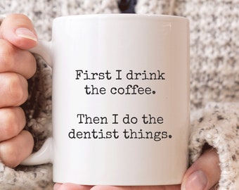 May include: White ceramic coffee mug with black text that reads "First I drink the coffee. Then I do the dentist things."