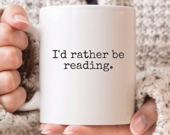 May include: White ceramic coffee mug with black text that reads "I'd rather be reading."