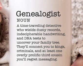 May include: White ceramic mug with a black and white definition of the word "Genealogist". The definition reads: "A time-traveling detective who wields dusty records, indecipherable handwriting, and DNA tests to uncover your family tree. They'll connect you to kings, criminals, and at least one overly prolific third cousin you'll regret messaging."