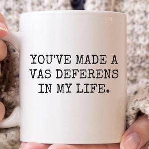 May include: White ceramic coffee mug with black text that reads "You've made a vas deferens in my life."