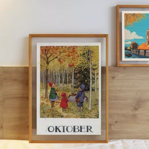 May include: A framed print with a vintage illustration of children in a forest with autumn leaves. The word "OKTOBER" is printed at the bottom. The frame is made of light brown wood. Another framed print is visible in the background.