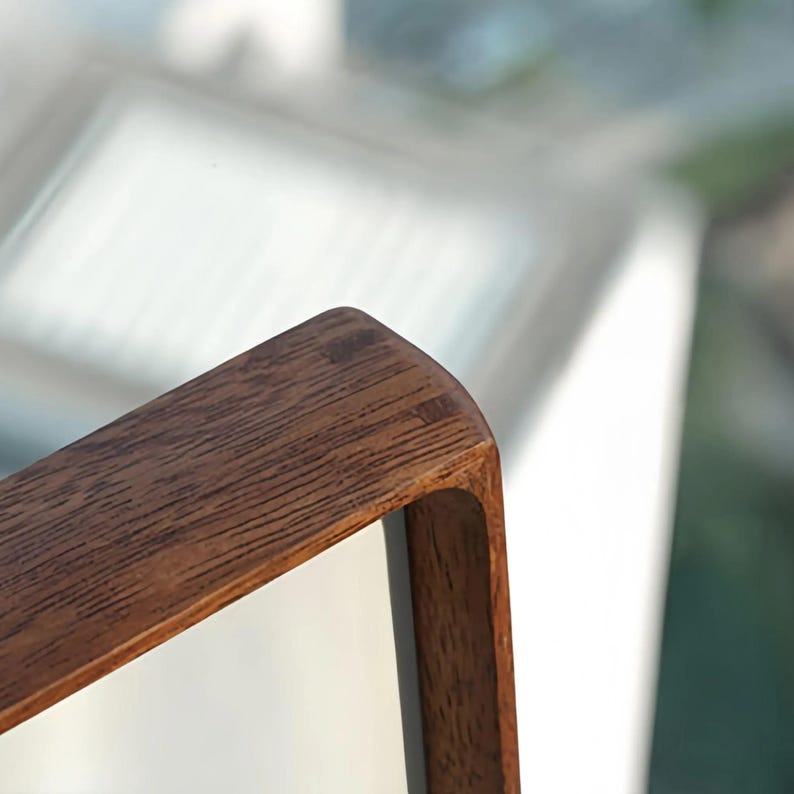 Close-up of a black walnut picture frame corner showing its smooth rounded profile, polished finish, and dark natural wood grain.