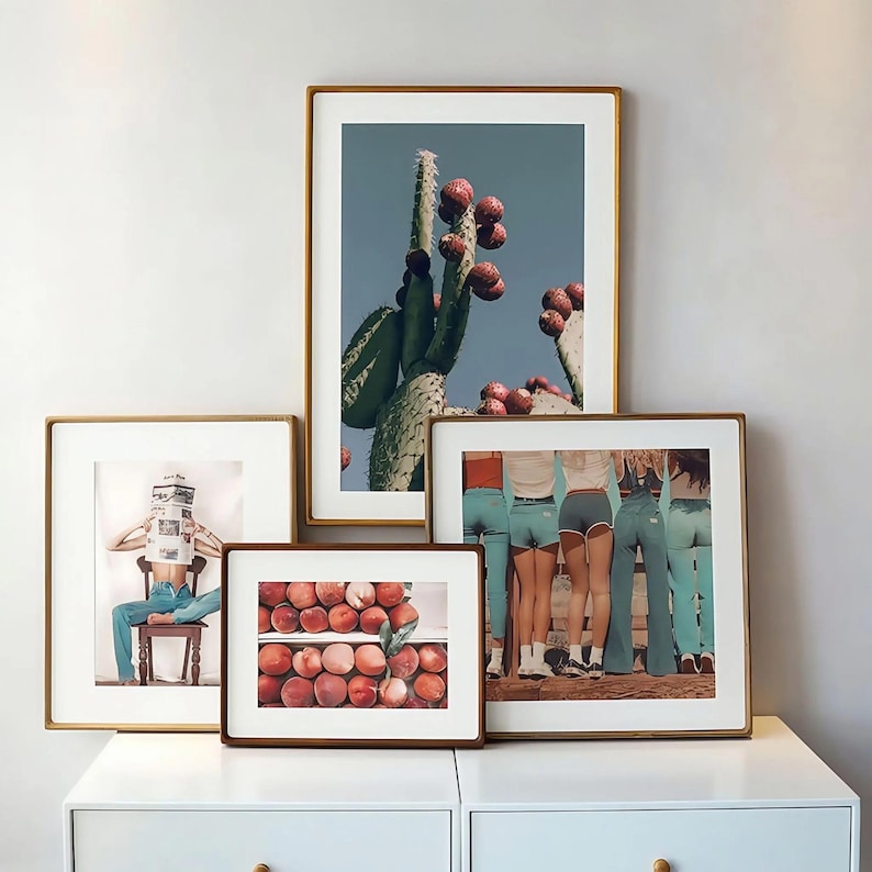 Four rounded-corner solid wood picture frames in vertical and horizontal sizes, arranged on a white console and displaying cactus, fruit, portrait, and group artwork.