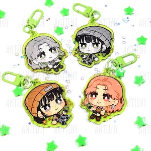 Może przedstawiać: Cztery breloczki do kluczy z postaciami z kreskówek z zielonymi akcentami. Każdy breloczek ma inny wzór postaci z telefonem. Breloczki mają zieloną obwódkę w kształcie gwiazdy i zielony klips. Zielone konfetti w kształcie gwiazdy jest rozrzucone.