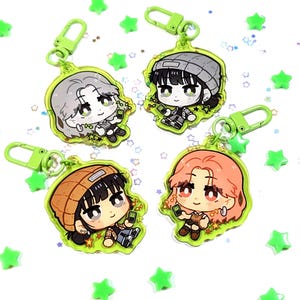 Peut inclure: Quatre porte-clés en acrylique avec des illustrations de personnages de dessins animés tenant un téléphone. Les porte-clés ont un bord vert et un fermoir vert. Les personnages ont différentes couleurs de cheveux et portent diverses tenues. Des confettis verts en forme d'étoile sont éparpillés.