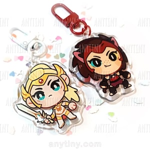 May include: Two acrylic keychains featuring cartoon characters. One keychain depicts a blonde character in gold armor holding a sword. The other keychain shows a character with brown hair and a red outfit. Both have a clear border and a red clasp.