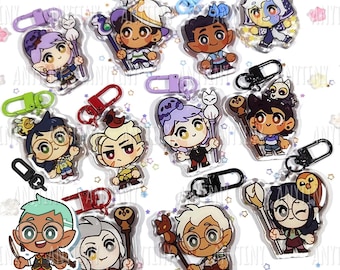 May include: A collection of colorful acrylic keychains featuring cartoon characters with various accessories. Each keychain has a metal clasp for easy attachment. The characters have distinct outfits and expressions, with some holding staffs or small animals.