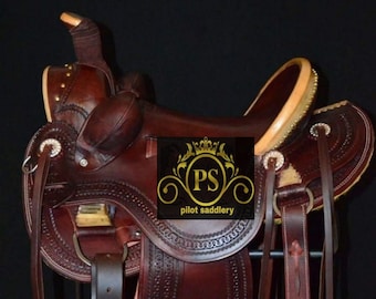 Puede incluir: Una silla de montar de cuero marrón con herramientas y costuras intrincadas. La silla de montar presenta un cantón de color crema y un logotipo 'PS pilot saddlery'.