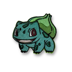 May include: Embroidered patch featuring a Bulbasaur design. The patch showcases a teal Bulbasaur with red eyes, a smiling mouth, and a green bulb on its back. The patch is likely for clothing or accessories.