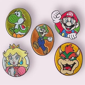 Könnte beinhalten: Fünf gestickte Bügelbilder mit Charakteren aus der Super Mario Bros. Videospiel-Reihe. Die Patches sind rund und zeigen Yoshi, Mario, Luigi, Peach und Bowser.