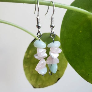 Könnte beinhalten: Ohrringe zum Hängen mit hellblauen, rosa und weißen Edelsteinchips. Die Ohrringe hängen an silberfarbenen Fischhaken-Ohrdrähten. Die Edelsteine sind in einem Kaskaden-Design angeordnet.
