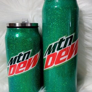 Puede incluir: Dos vasos aislados de purpurina verde con un logotipo de Mountain Dew. Los vasos tienen la forma de una lata.