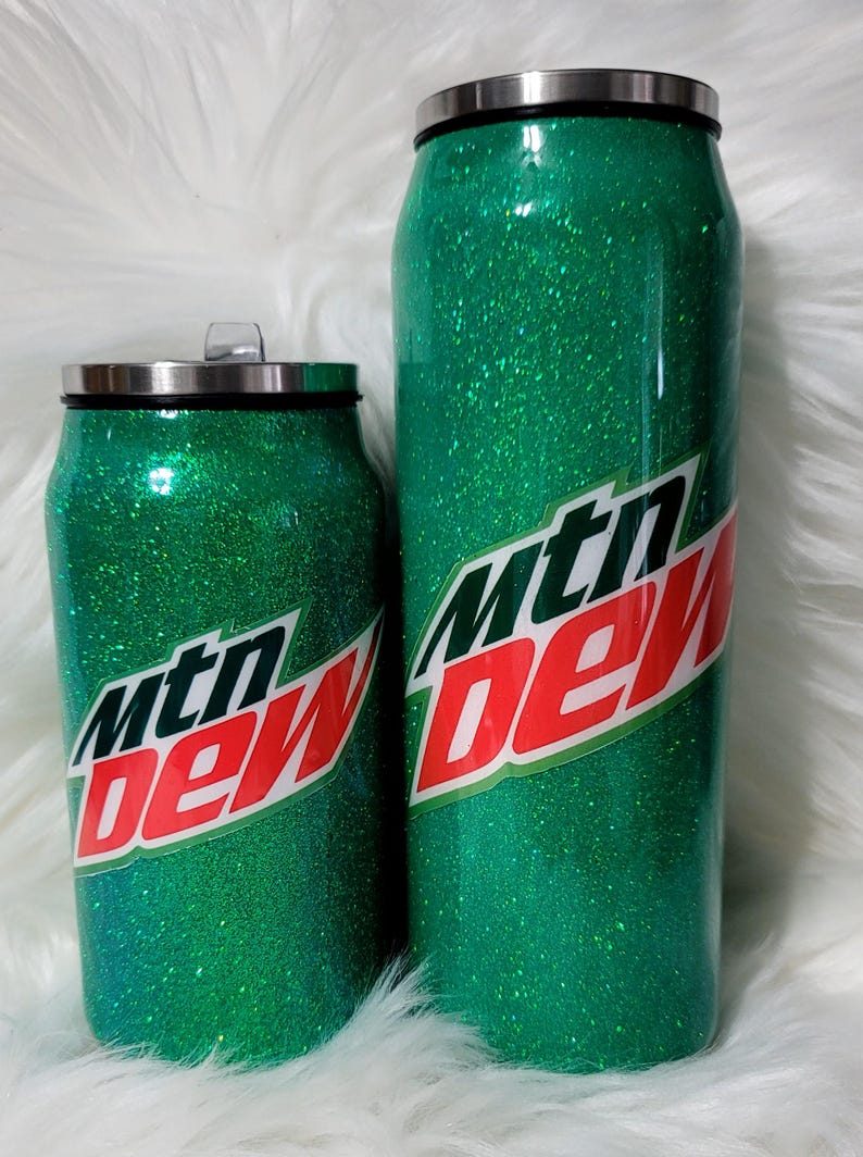 Puede incluir: Dos vasos aislados de purpurina verde con un logotipo de Mountain Dew. Los vasos tienen la forma de una lata.