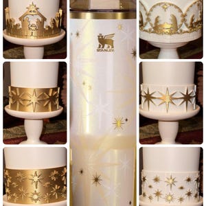 May include: White insulated tumbler with gold star and snowflake accents. The tumbler features the Stanley logo and a gold rim. Additional images show white candle holders with gold star and nativity scene designs.