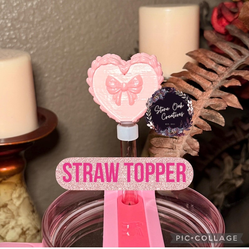 May include: A pink straw topper with a heart design and a bow in the centre. The text "STRAW TOPPER" is displayed in pink glitter. The topper is attached to a pink tumbler.