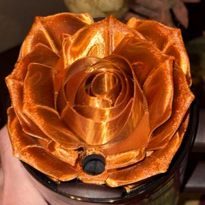 May include: A 3D printed rose-shaped bottle stopper in a copper color. The rose is made of multiple layers of petals.