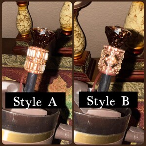 May include: Two decorative bottle stoppers, labeled Style A and Style B. Style A features a cylindrical design with rectangular crystals. Style B has a similar shape, adorned with smaller, irregularly shaped crystals. Both have a dark stem.