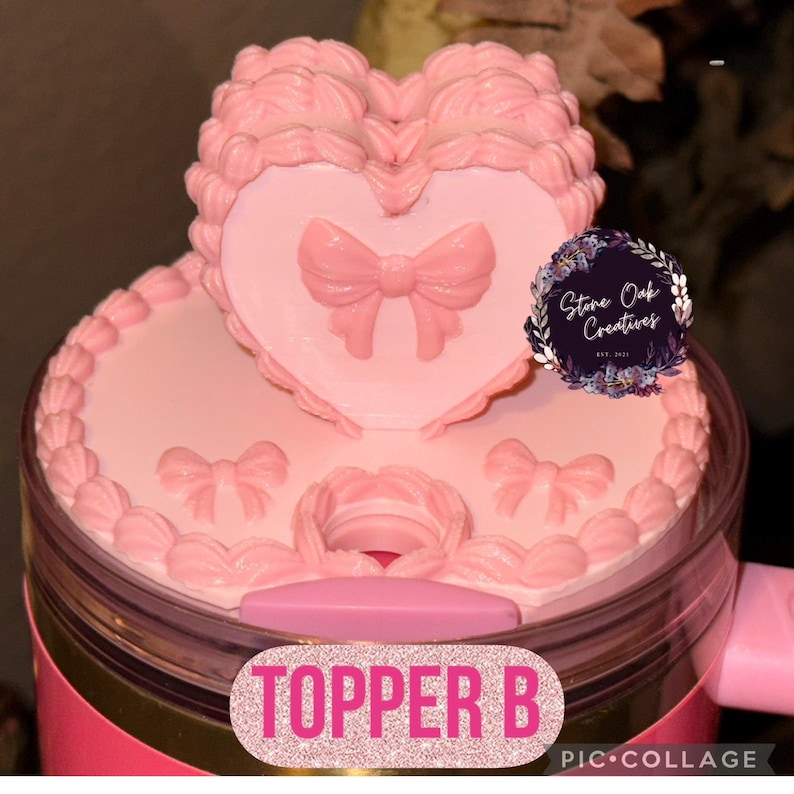 May include: A pink tumbler topper with a heart-shaped design and bow accents. The topper features the text "TOPPER B" in a glittery font. The design includes a decorative border and a logo that says "Stone Oak Creatives".