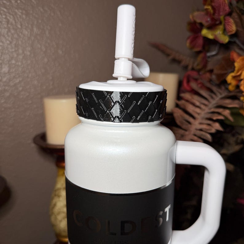 May include: White insulated water bottle with a black band and a white handle. The bottle has a black and white lid with a white spout. The text "COLDEST" is visible on the bottle.
