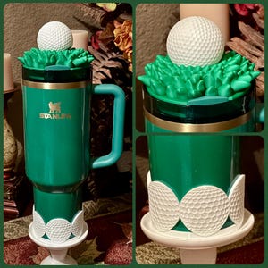 May include: Green Stanley mug with a golf theme. The mug features a golf ball on top of a green turf design, with a golf ball accent at the base. The Stanley logo is visible in gold. A unique gift for golf enthusiasts.