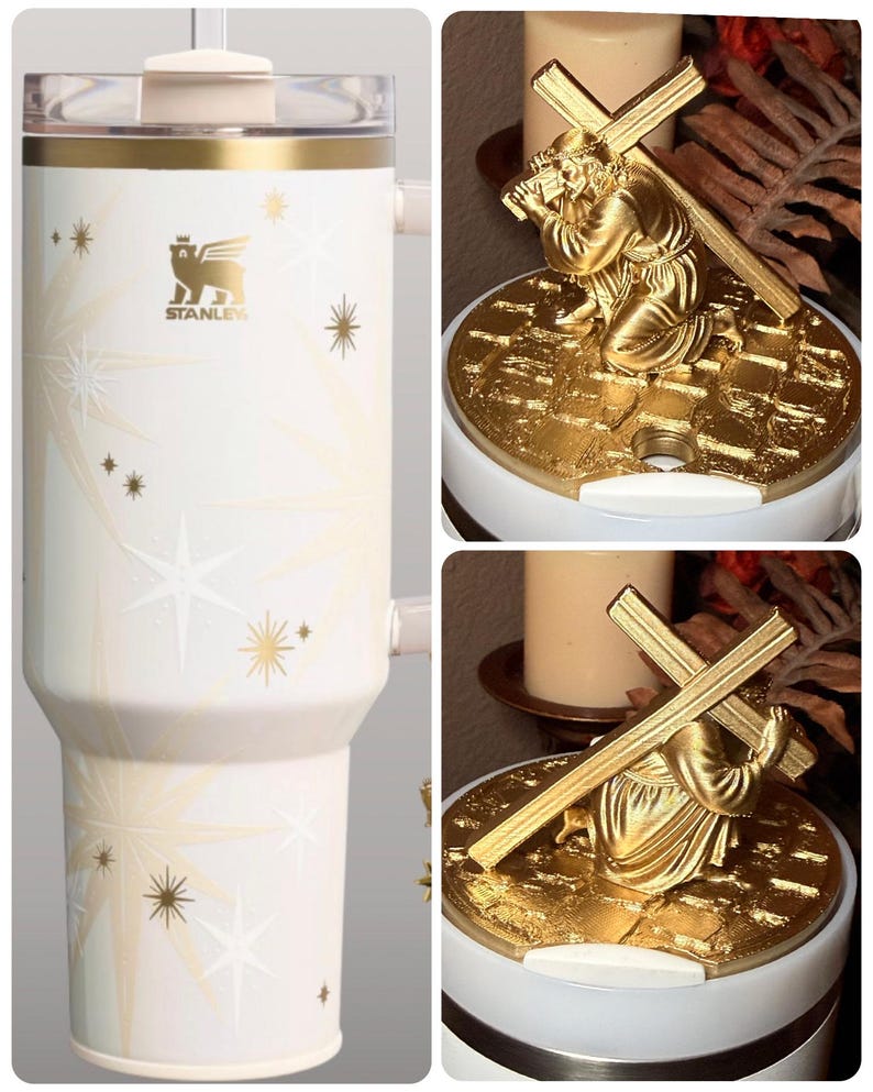 Puede incluir: Un vaso Stanley blanco con detalles dorados y dise&ntilde;os de estrellas. El vaso tiene una tapa transparente y un asa. Una figura religiosa dorada representa a una persona arrodillada que lleva una cruz.