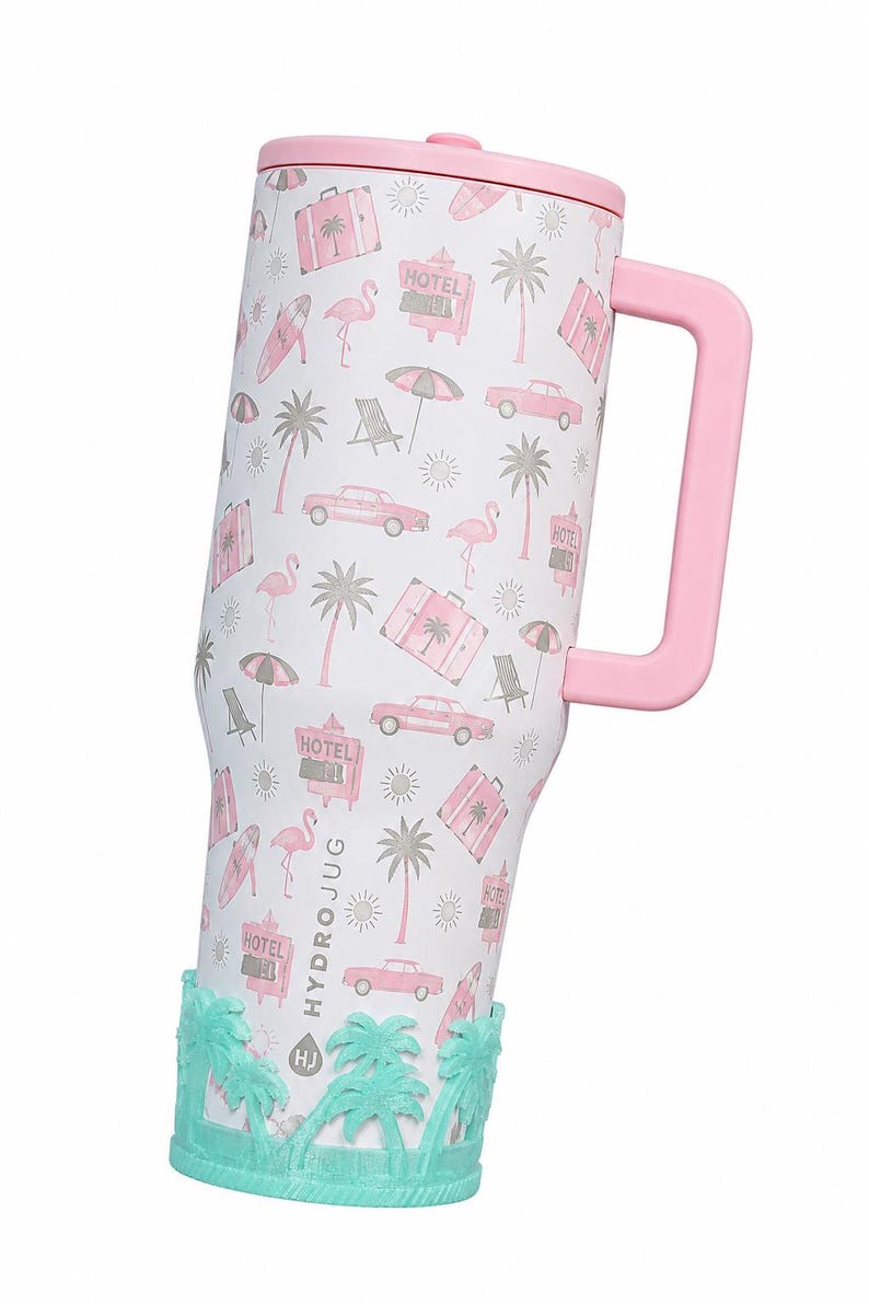 May include: A white tumbler with a pink handle and lid, featuring a repeating pattern of pink flamingos, palm trees, vintage cars, suitcases, umbrellas, and hotel signs. The base has a textured mint green silicone sleeve with palm tree motifs.