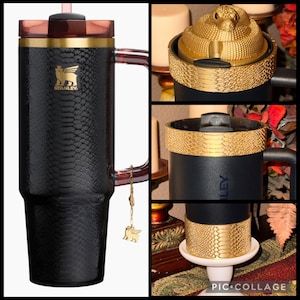 May include: Black and gold Stanley travel mug with a snake-skin texture. The mug has a handle, a gold rim, and a gold charm. The lid is gold with a snake design. The mug has the Stanley logo.