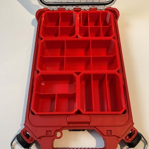 May include: Red plastic storage box with a clear lid and multiple compartments. The box has a handle and two latches.