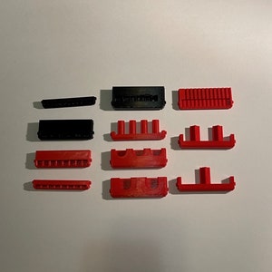 May include: A set of 10 black and red plastic connector pieces. The pieces are various shapes and sizes, and some have small holes or slots.