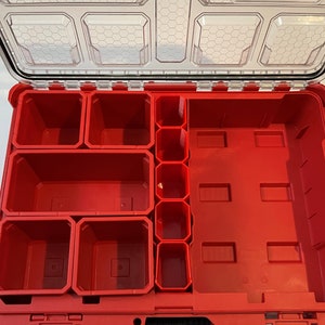 May include: An open red plastic storage box with multiple compartments of various sizes. The box is empty and ready to be organised.