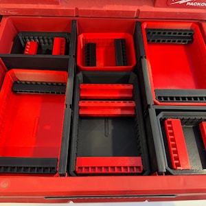 May include: Red and black tool organiser with multiple compartments. The organiser is divided into various sections, with red and black trays and holders. The compartments are designed to hold tools and accessories, providing organisation and easy access.