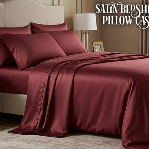 Könnte beinhalten: Ein Bett ist mit einem Set aus bordeauxfarbenen Satin-Bettlaken und Kissenbezügen bezogen. Die Laken sind ordentlich auf dem Bett angeordnet, mit den Kissenbezügen obenauf. Der Text "SATIN BED SHEETS PILLOW CASES" wird oben rechts angezeigt.