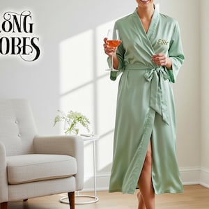 May include: A light green satin robe with a wrap design and a matching tie. The robe has wide sleeves and is embroidered with the name "Ellie". The words "Long Robes" are in a script font in the upper left corner.