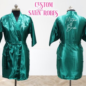 May include: Two green satin robes with white text. One robe says "Mother of Bride" and the other says "Ava".