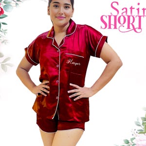 May include: A red satin short-sleeved pajama set with white piping. The top has a button-up front and a pocket with the name "Harper" embroidered on it.