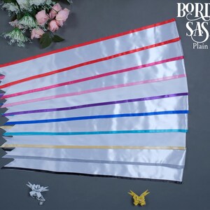 May include: White satin sashes with colored ribbon stripes in red, pink, purple, blue, teal, yellow, gray, and black. The sashes have a pointed edge. The text "BORDER SASH Plain" is in the upper right corner.